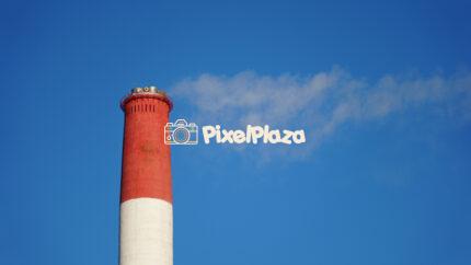 Industrial Chimney with Smoke Against a Clear Blue Sky